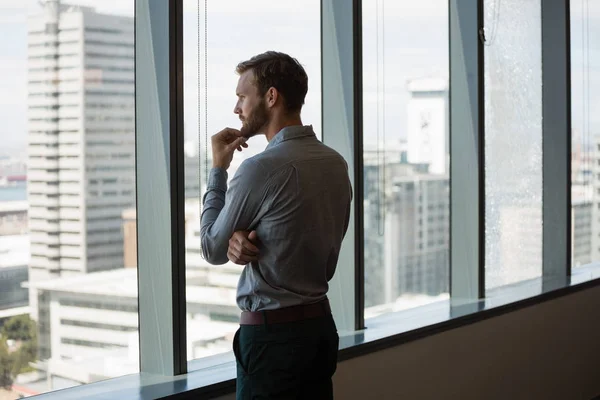 Male executive looking through window — Stock Photo, Image