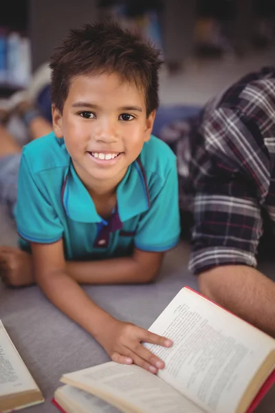 Schooljongen lezing boek in bibliotheek — Stockfoto