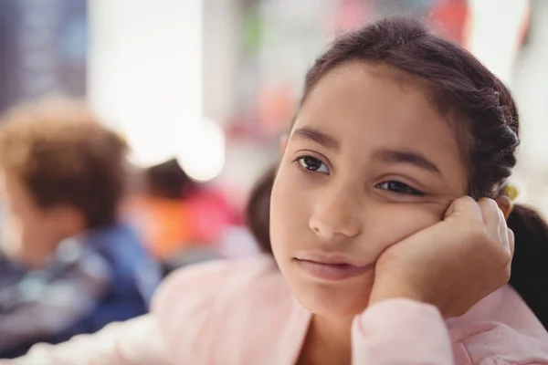 Nachdenkliches Schulmädchen sitzt im Klassenzimmer — Stockfoto