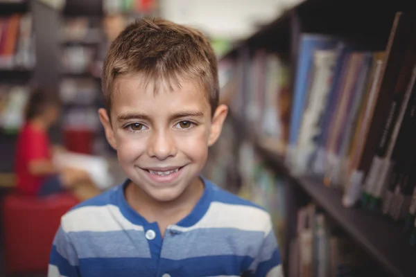 Lachende schooljongen permanent in bibliotheek — Stockfoto
