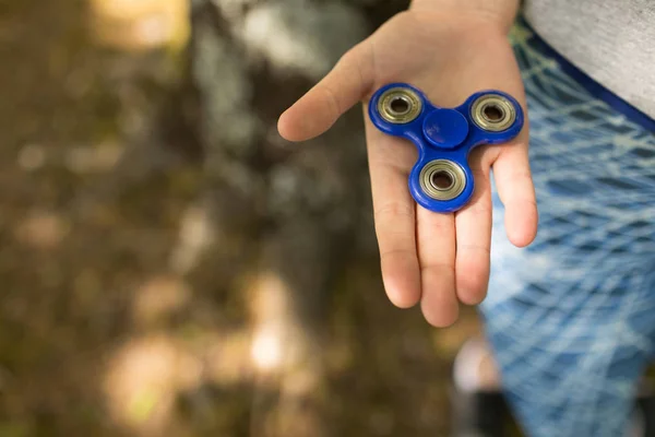 Menina segurando um fidget spinner em um parque — Fotografia de Stock