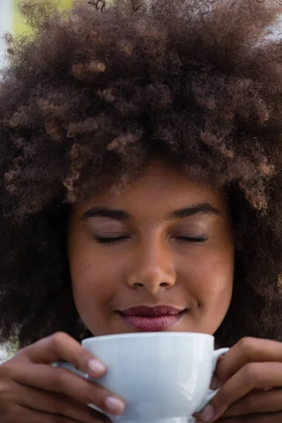 Женщина с кудрявыми волосами, нюхающая кофе — стоковое фото
