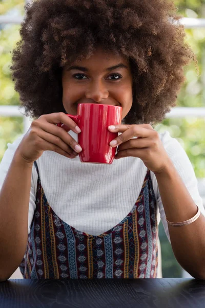 Mujer con el pelo muy rizado tomando café en la cafetería —  Fotos de Stock