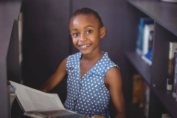 Skolflicka läsa bok i biblioteket — Stockfoto