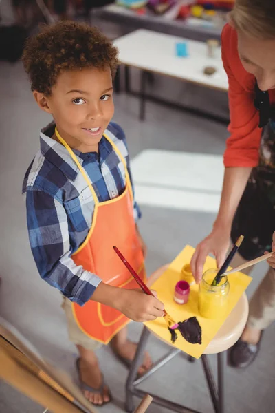 Teacher assisting schoolboy in drawing class — Stock Photo, Image