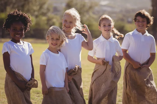 Счастливые школьницы развлекаются во время забега с мешком в парке — стоковое фото