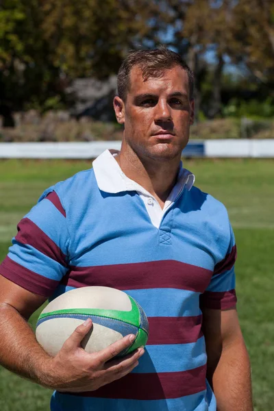 Jogador de rugby segurando bola no campo — Fotografia de Stock