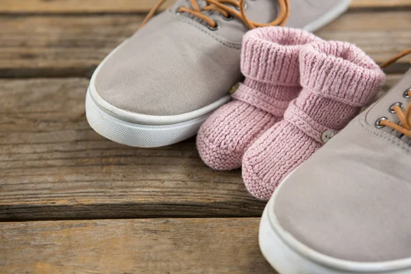 Schuhe und Babystiefel auf Holztisch — Stockfoto