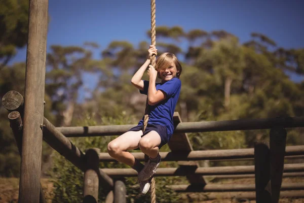 Menina escalando corda durante curso de obstáculo — Fotografia de Stock