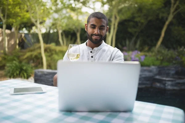 Hombre con copa de vino usando portátil — Foto de Stock