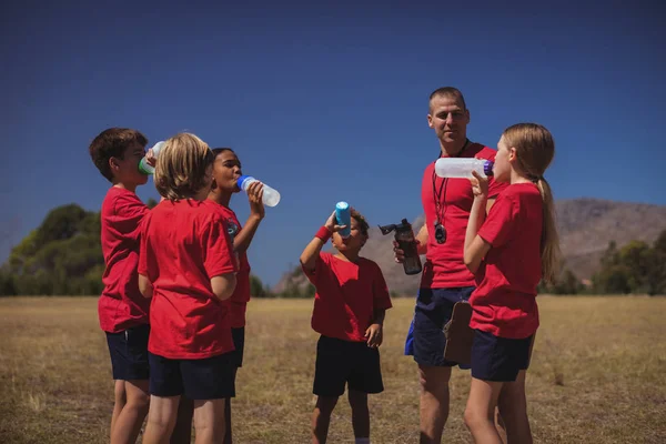 Entrenador y niños bebiendo agua —  Fotos de Stock