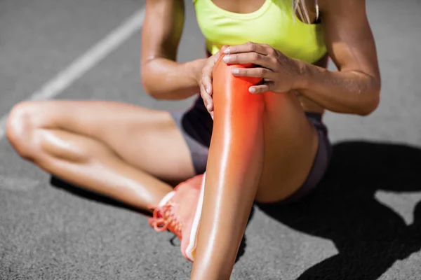 Atleta feminina sentada na pista com dor — Fotografia de Stock