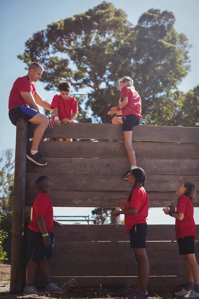 Trener wspierające dzieci wspinać się — Zdjęcie stockowe