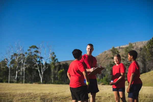 Entrenador con niños discutiendo en el campo de entrenamiento —  Fotos de Stock