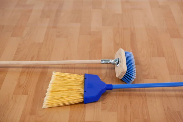 Escobas de barrido en el suelo de madera — Foto de Stock