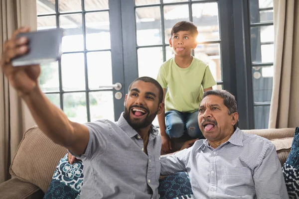 Família fazendo rosto enquanto toma selfie em casa — Fotografia de Stock