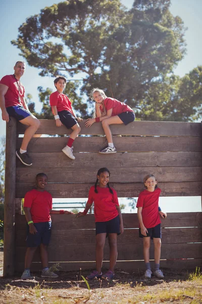 Trener i dzieci siedząc na drewnianych ścian — Zdjęcie stockowe