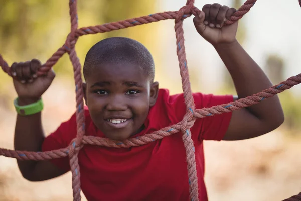 Boy climbing a net during obstacle course — Stock Photo, Image