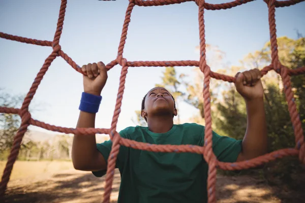 Determined boy climbing net — Stock Photo, Image