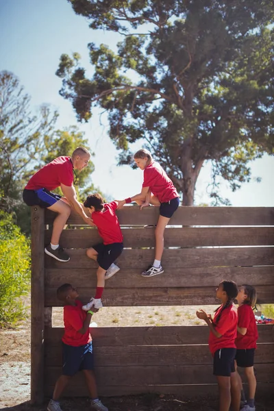 Trainer assisting kids to climb — Stock Photo, Image