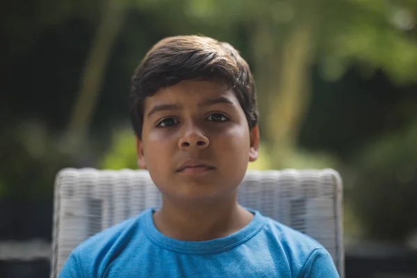 Sério menino sentado na cadeira — Fotografia de Stock