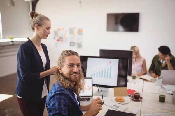 Smiling businessman sitting at office desk — Stock Photo, Image