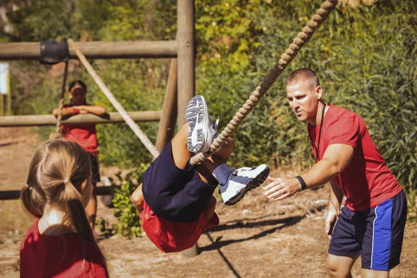 Trainer assisting boy at boot camp — Stock Photo, Image