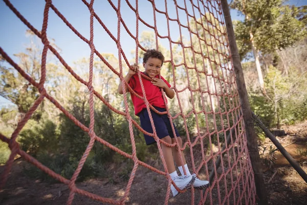 Boy climbing a net during obstacle course — Stock Photo, Image