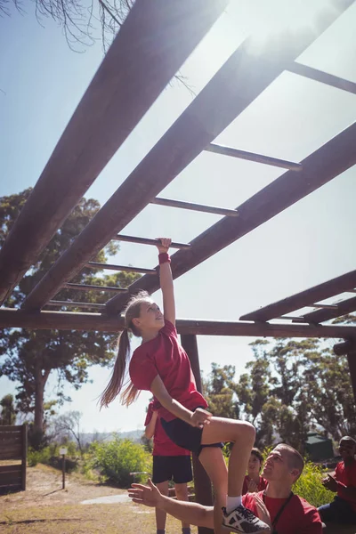 Trainer assisting girl to climb — Stock Photo, Image