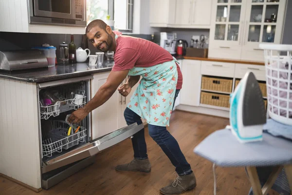 食器洗い機に食器を置く男 — ストック写真