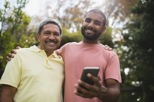 Leende far och son med mobiltelefon — Stockfoto