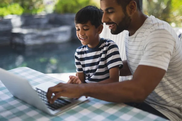 Homem com seu filho usando laptop no alpendre — Fotografia de Stock