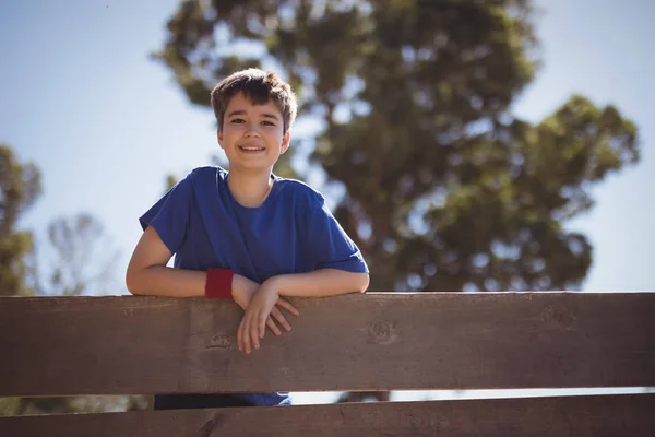 Happy boy standing on wooden wall — Stock Photo, Image