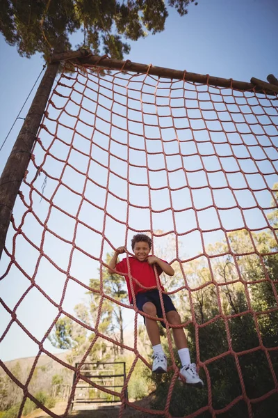 Niño escalando red durante carrera de obstáculos — Foto de Stock