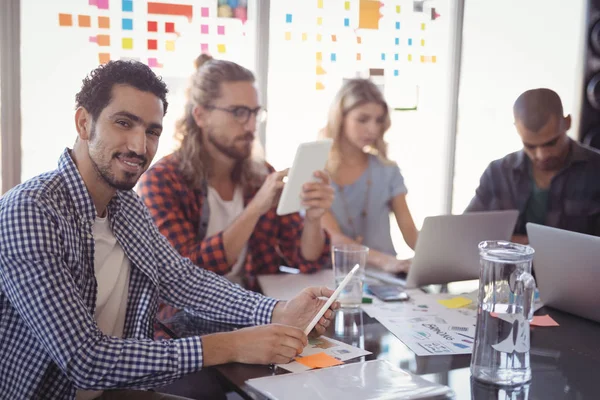 Businessman sitting with colleagues at desk — Stock Photo, Image