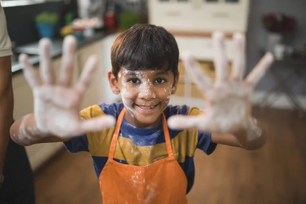 Menino mostrando as mãos bagunçadas na cozinha — Fotografia de Stock