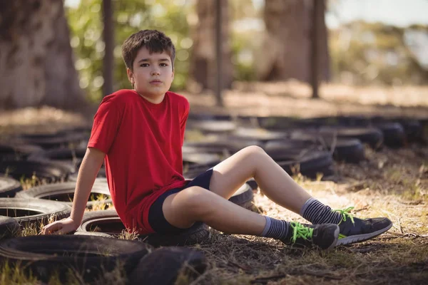 Niño relajándose en el neumático durante la carrera de obstáculos — Foto de Stock