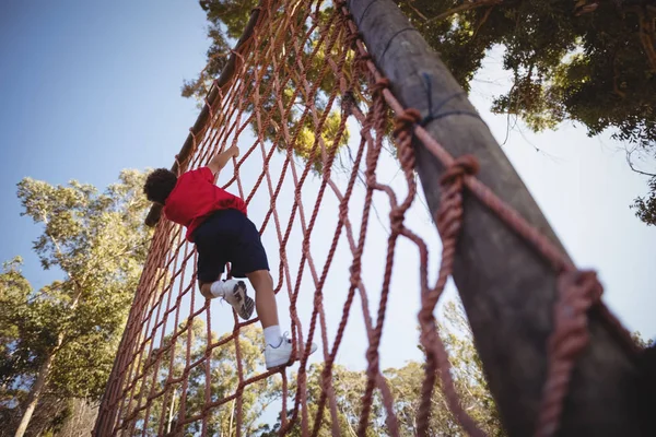 Chico escalando una red durante carrera de obstáculos — Foto de Stock