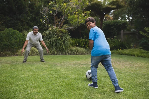 Pojke spela fotboll med morfar på park — Stockfoto