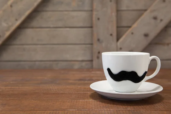Кавова чашка з вусами на столі — стокове фото
