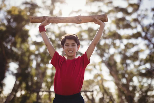 Boy exercising with log during obstacle course — Stock Photo, Image