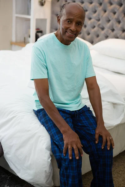 Homme âgé souriant assis sur le lit — Photo