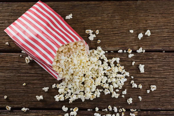 Rozptýlené popcorn na dřevěný stůl — Stock fotografie