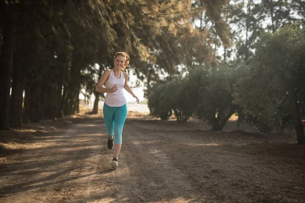 Frau joggt bei sonnigem Wetter auf Feldweg — Stockfoto