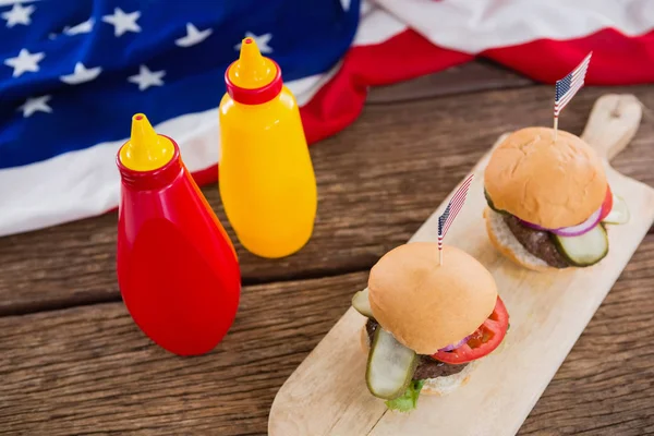 Amerykańską flagę i hamburgery na drewnianym stole — Zdjęcie stockowe