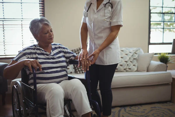 Doctor interactuando con la mujer mayor en silla de ruedas — Foto de Stock