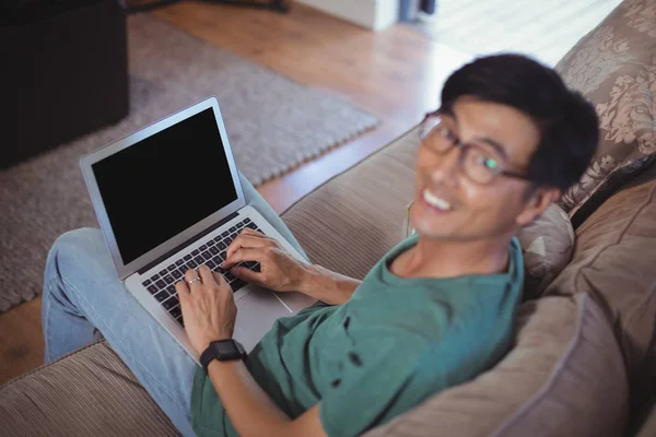 Uomo utilizzando il computer portatile in soggiorno — Foto Stock