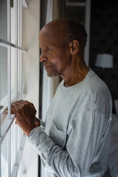 Senior schaut aus Fenster — Stockfoto