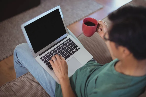 Uomo utilizzando il computer portatile in soggiorno — Foto Stock