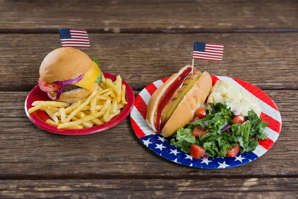 Hamburger a párek v rohlíku na dřevěný stůl — Stock fotografie